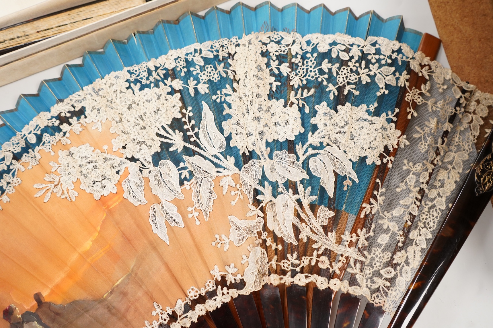 A gold mounted lace and hand painted fan and three others to include a lacquered example, one cased
